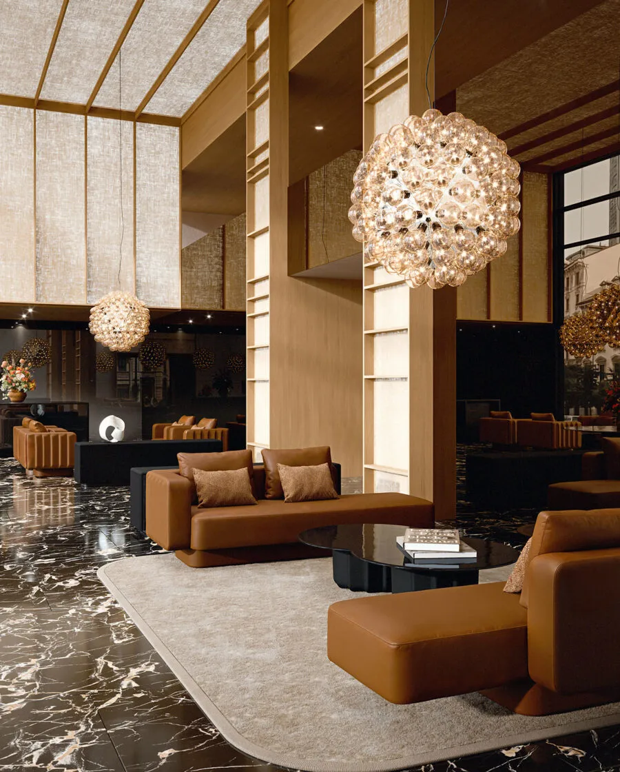 Sabree luxury sofa in cognac upholstery in a luxury hotel lobby with black marble floor, fireplace and crystal chandeliers — Italian design