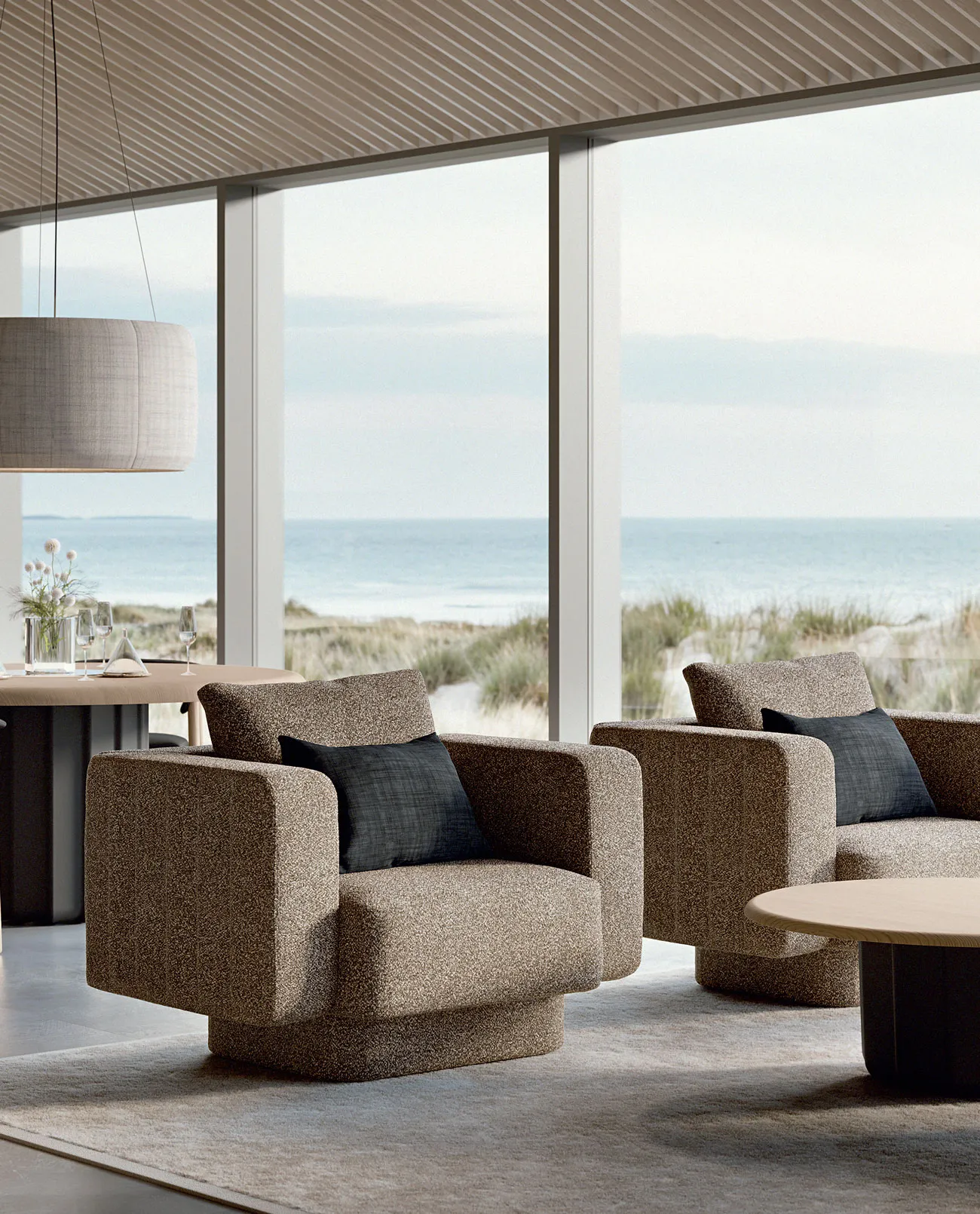 Sabree luxury sofa in taupe upholstery with blue cushions in a coastal living room with floor-to-ceiling windows and sea view — Italian design