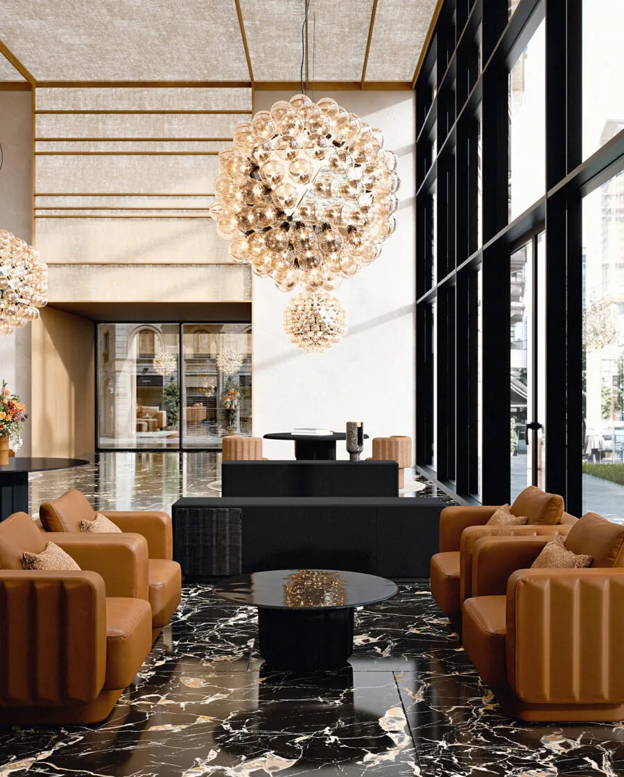Sabree designer armchair in cognac upholstery in a luxury hotel lobby with crystal chandeliers and floor-to-ceiling windows — Italian design