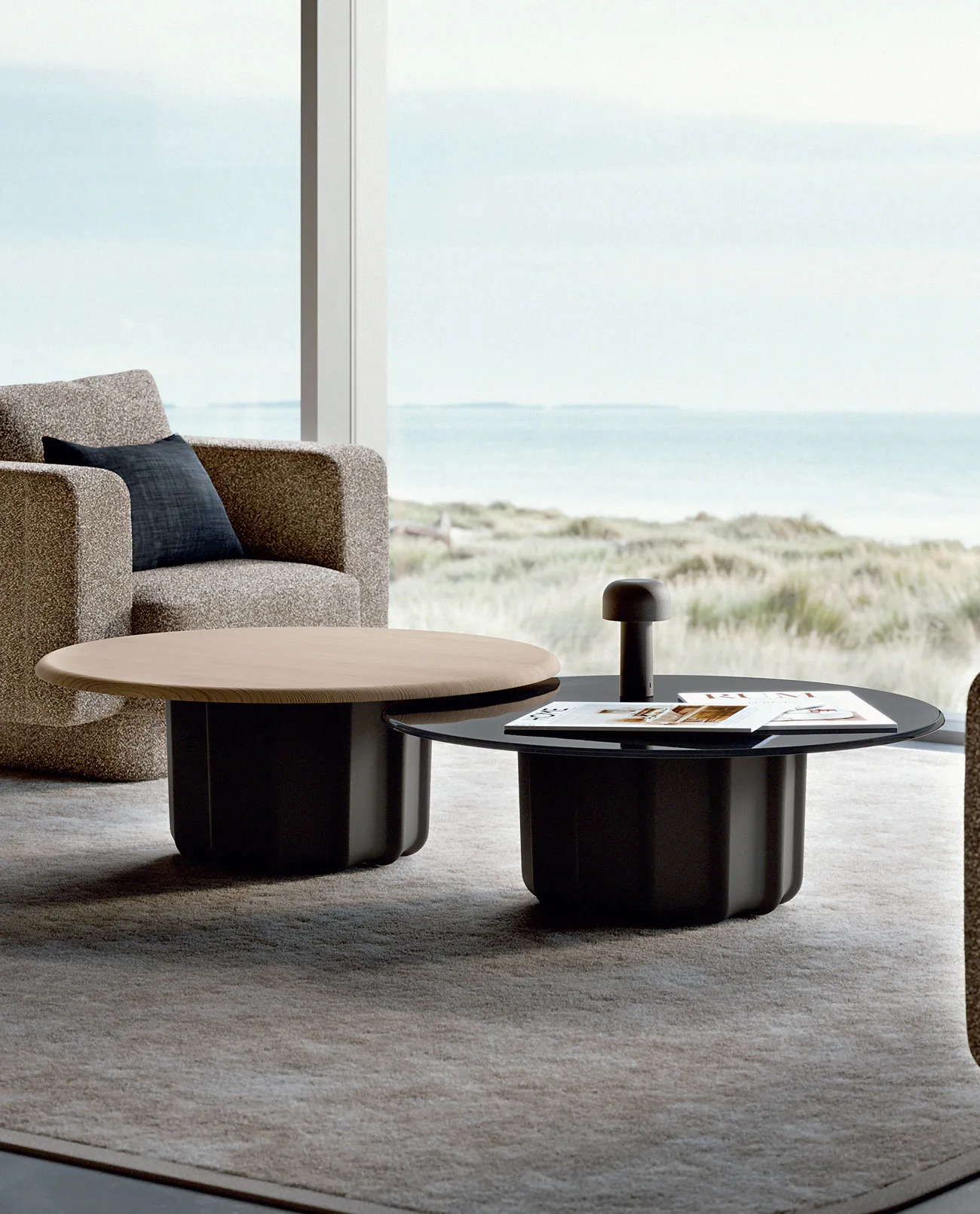 Sabree luxury coffee table with dark sculptural base and oak top in a coastal living room with dunes and sea view — Italian design