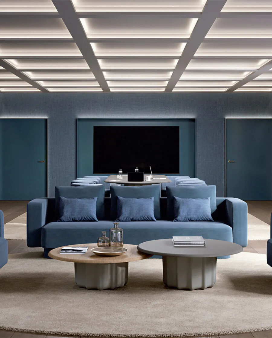 Sabree luxury coffee table with sculptural base in a refined home theater room with coffered luminous ceiling and deep blue sofas — Italian design