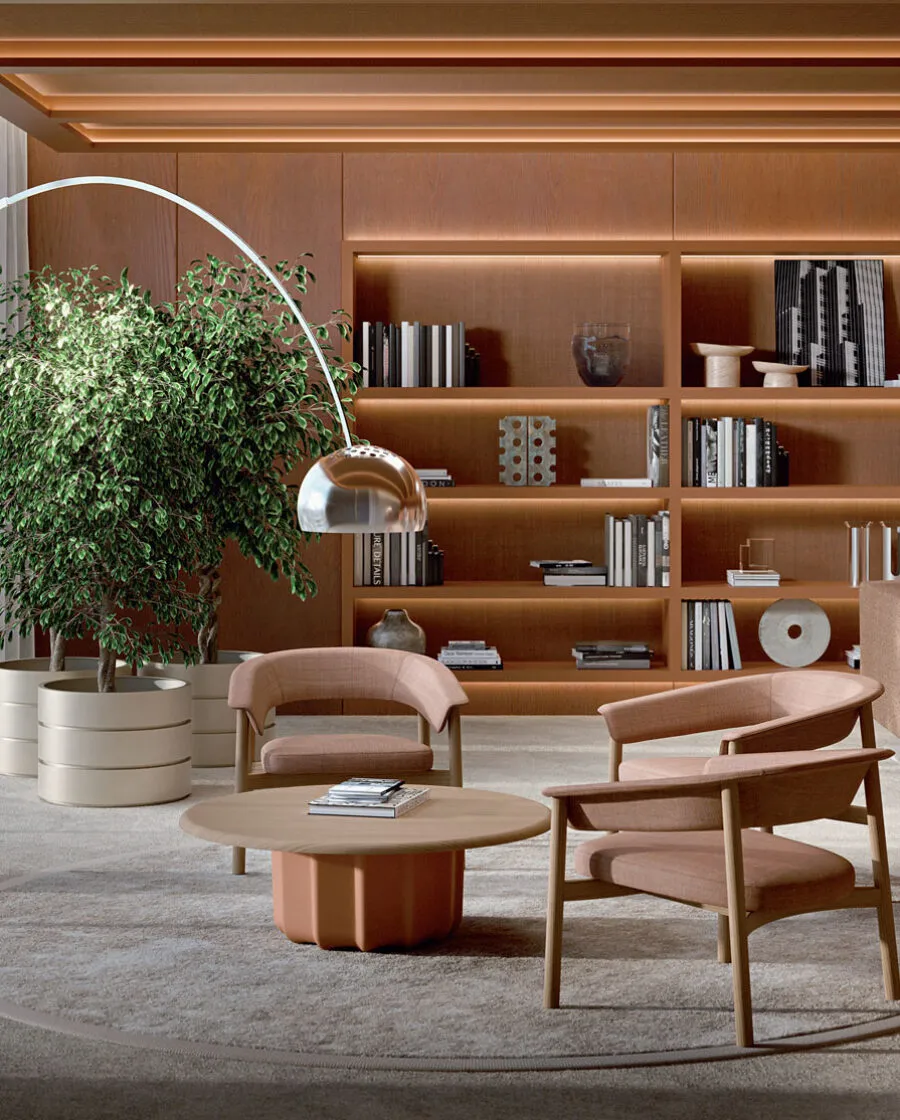 Sabree round luxury coffee table in a warm private library with wooden shelving, cognac leather armchair and arc floor lamp — Italian design